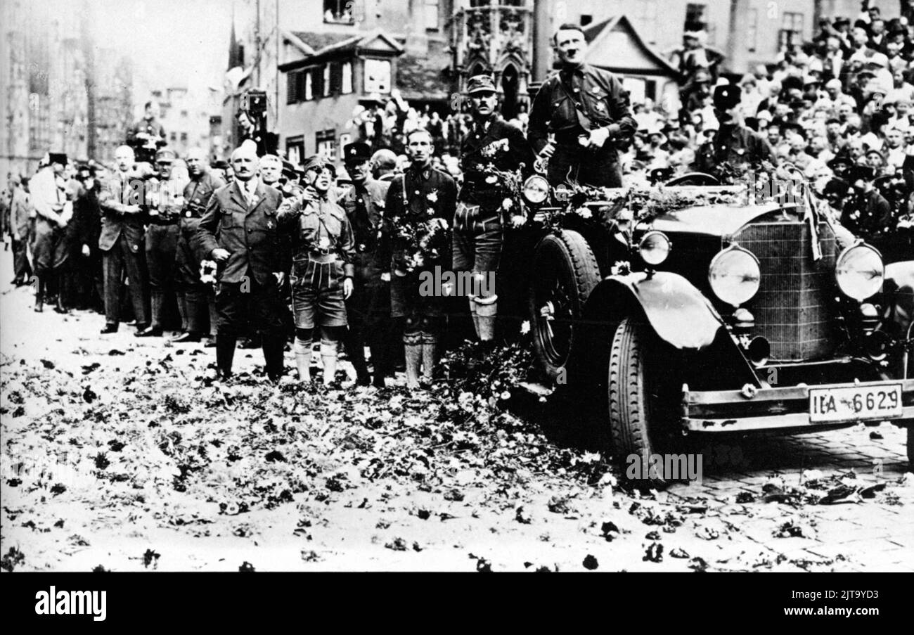 Ein Vintage-Foto um den 1 1929. August in Nürnberg, das den zukünftigen deutschen Nazi-Diktator Adolf Hitler zeigt, der in einem offenen Mercedes-Wagen posiert und während einer Party-Kundgebung Blumen wirft Stockfoto