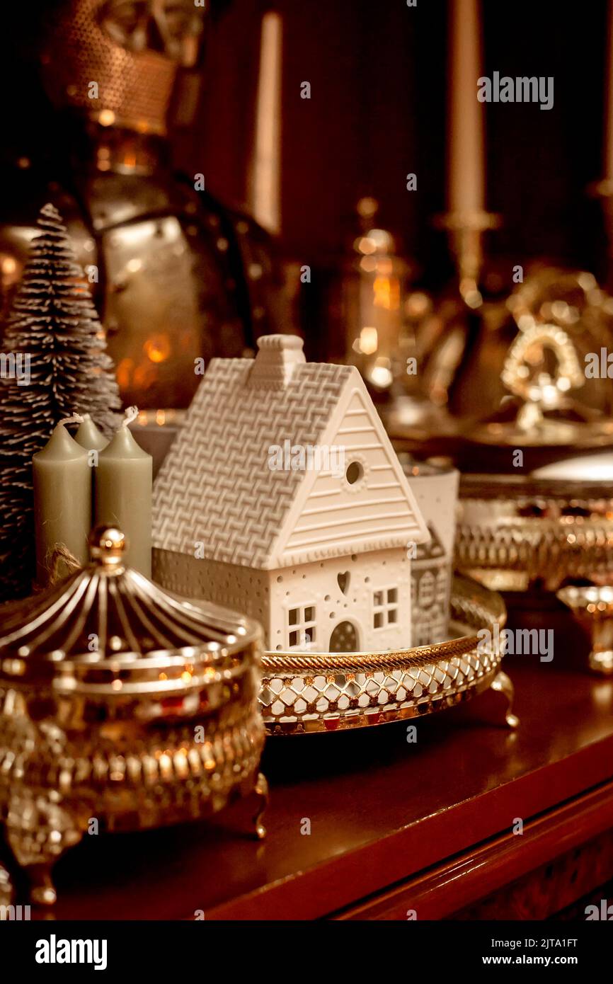 Weihnachtliche Innenraumdetails im Regal im Raum. Haus, Kerzen, Kerzenständer, Glas, Zuckerdose, Weihnachtsbaum. Stockfoto