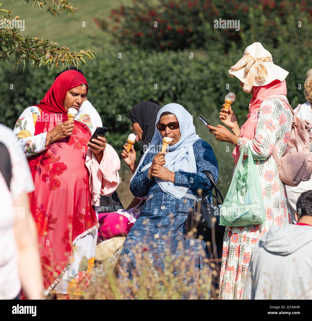 Muslimische Frauen in traditioneller Kleidung oder Urlaub beim Eisessen am Lake Windermere Cumbria UK Stockfoto