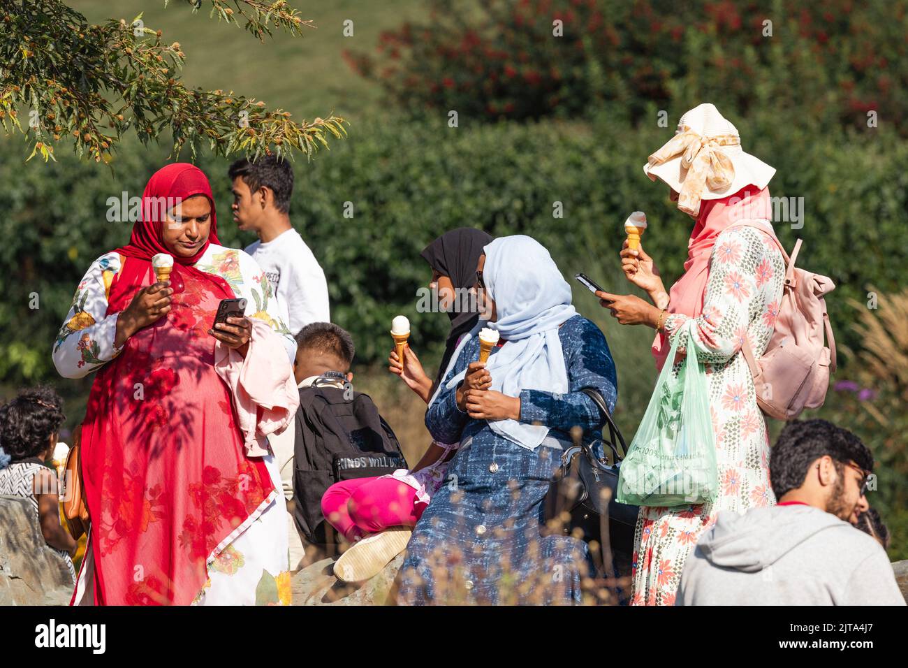 Muslimische Frauen in traditioneller Kleidung oder Urlaub beim Eisessen am Lake Windermere Cumbria UK Stockfoto
