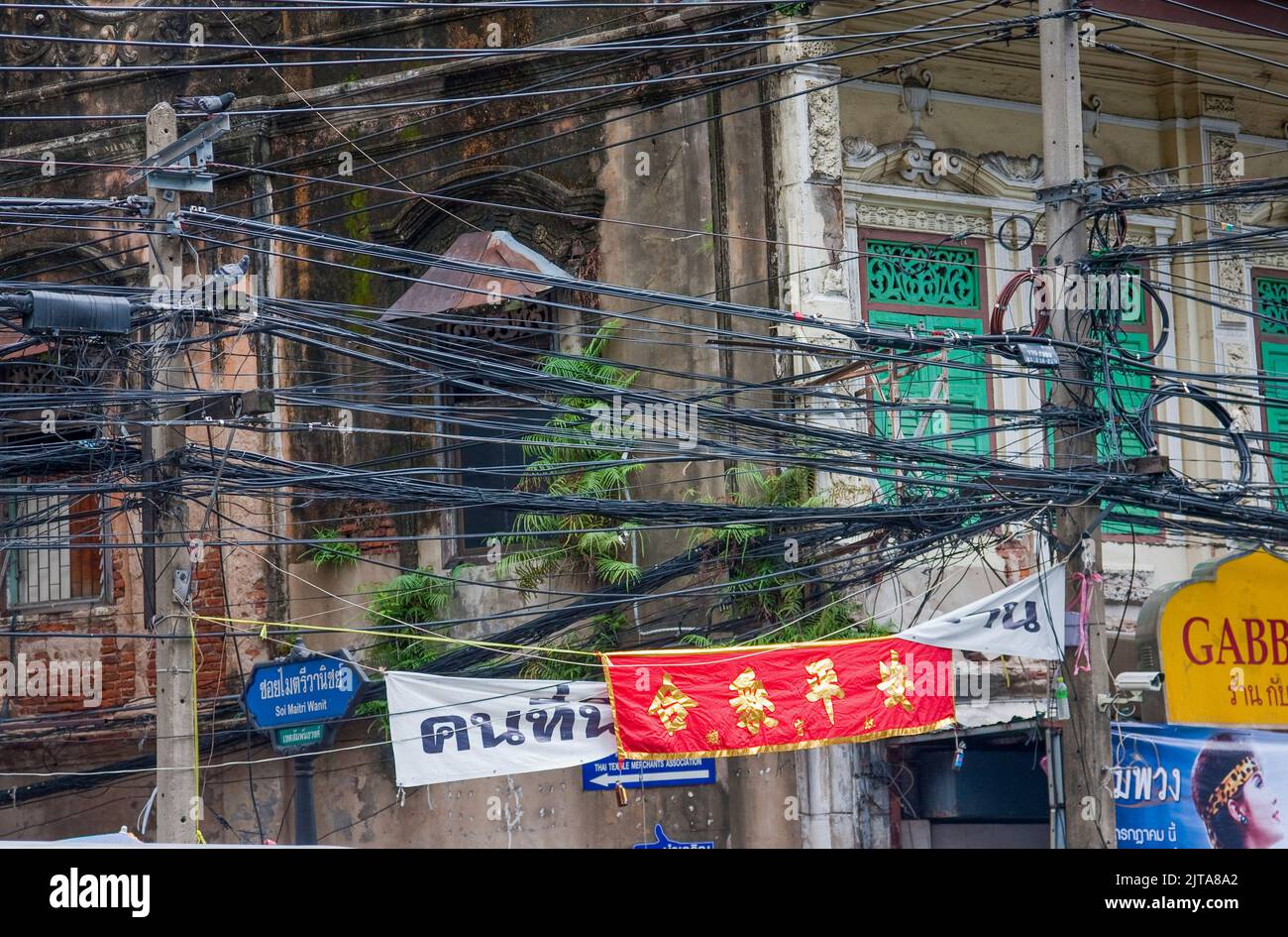 Thailand, Bangkok. Altes historisches Gebäude mit Strom- und Telefonleitungen, die draußen über der Straße hängen. Stockfoto