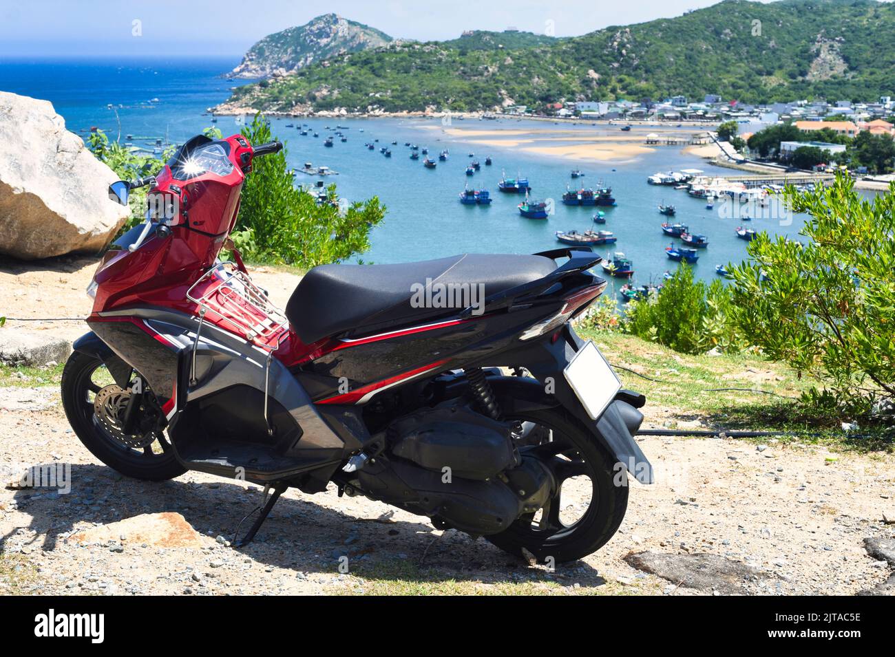 Rotes Motorrad vor einem Blick auf das vietnamesische Fischerdorf Stockfoto