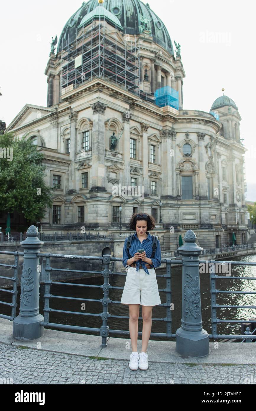 BERLIN, DEUTSCHLAND - 14. JULI 2020: Junger lockiger Tourist mit Smartphone vor dem berliner Dom, Stockbild Stockfoto