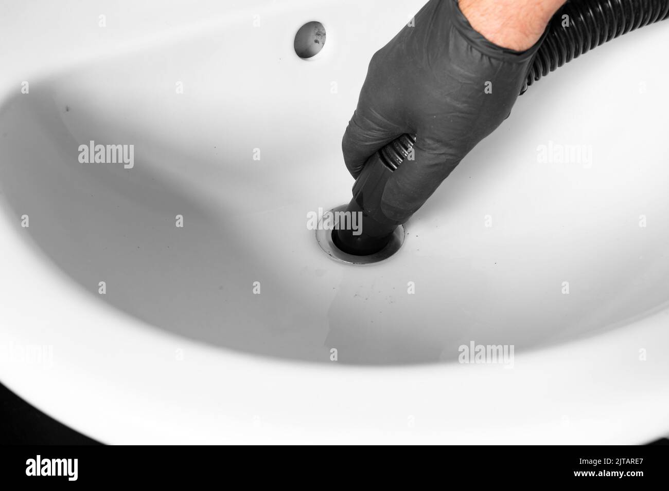 Mann entblockierte Rohre in einem Waschbecken mit einem staubsauger. Machen Sie es selbst Wartungskonzept Stockfoto