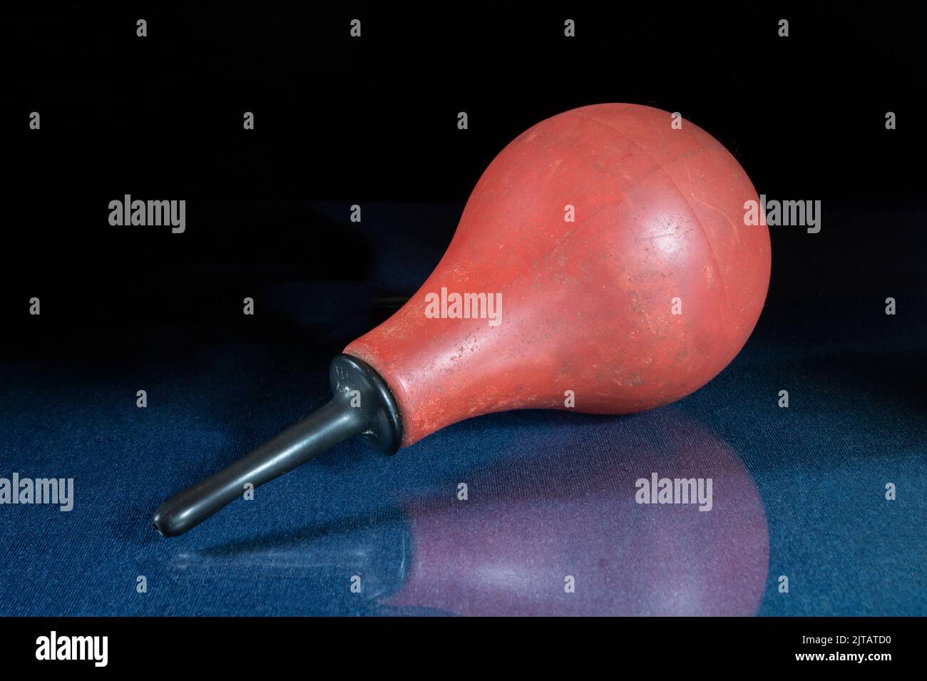 Medizinisches Instrument zur Behandlung auf einem Glastisch. Eine Gummibirne auf schwarzem Hintergrund. Stockfoto