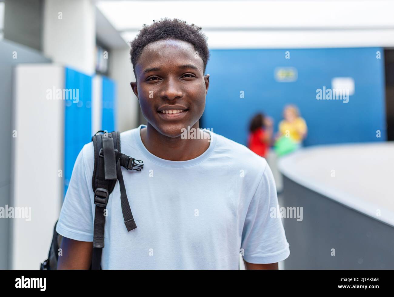Porträt eines jungen afroamerikanischen Studenten, der auf dem Korridor der Highschool steht Stockfoto
