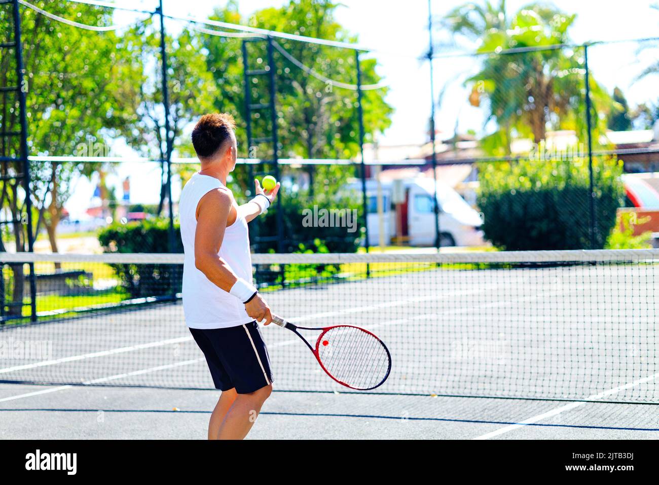 Älterer kaukasischer Mann, der auf dem Tennisplatz Tennis spielt und tagsüber im Freien an der frischen Luft Tennisschläger hält Stockfoto