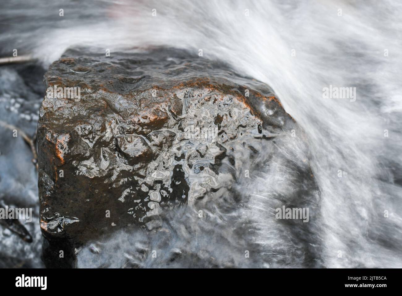 Lange Exposition Nahaufnahme eines Steines oder Felsens im Fluss, Wasser fließt Stockfoto