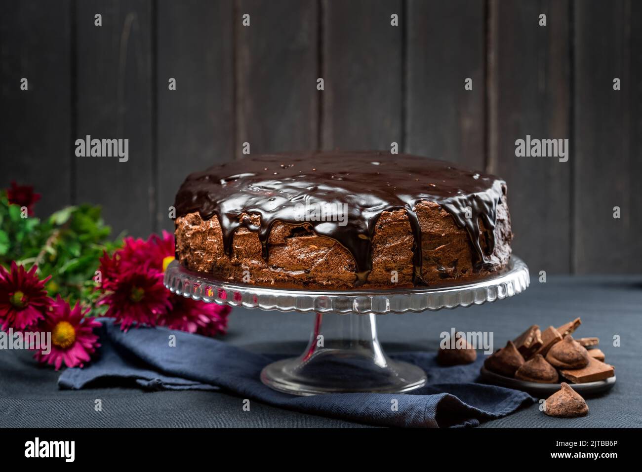 Köstliche hausgemachte dunkle Schokolade Kuchen Dessert mit Ganache Glasur Belag auf dem Kuchen stehen über dunklen rustikalen Holzhintergrund Stockfoto