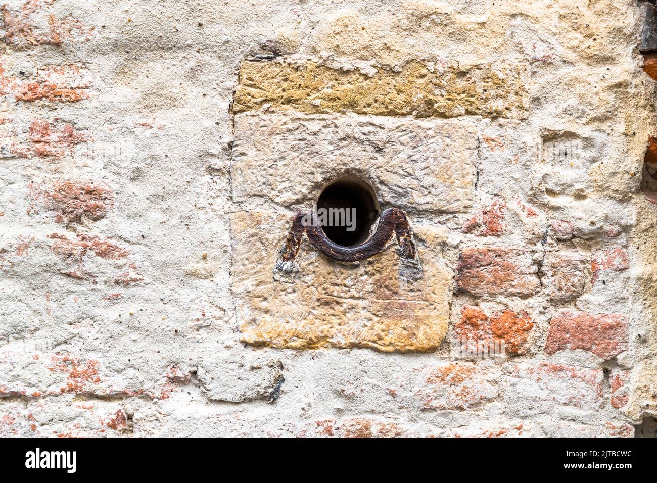 Solche Löcher können in Deventer (Niederlande) in gegenüberliegenden Häusern der engen Straßen gefunden werden. Während der Besiege wurden Ketten über die Gassen gestreckt, so dass feindliche Reiter nicht durchkommen konnten Stockfoto