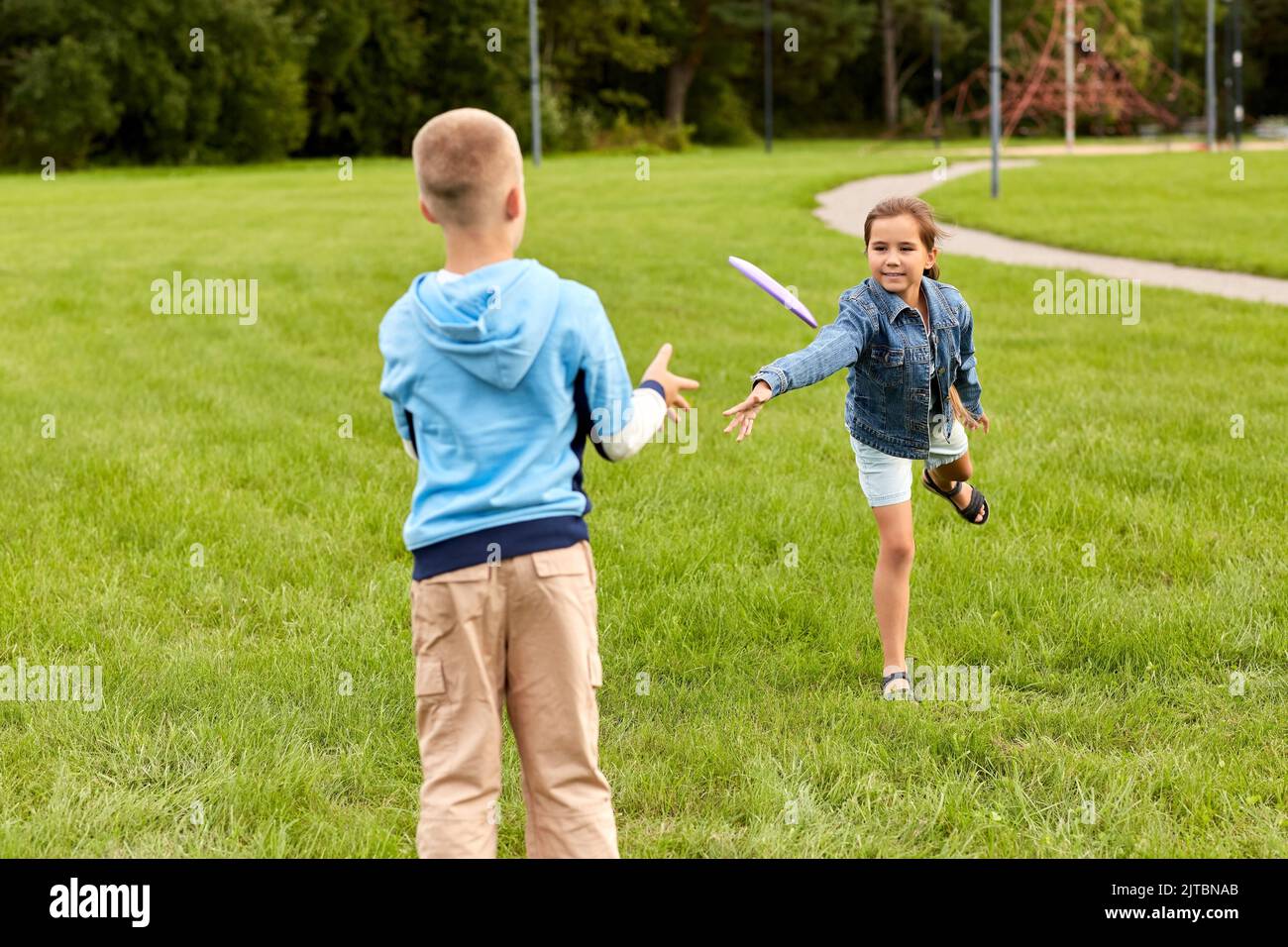 Glückliche Kinder, die im Park mit fliegender Scheibe spielen Stockfoto