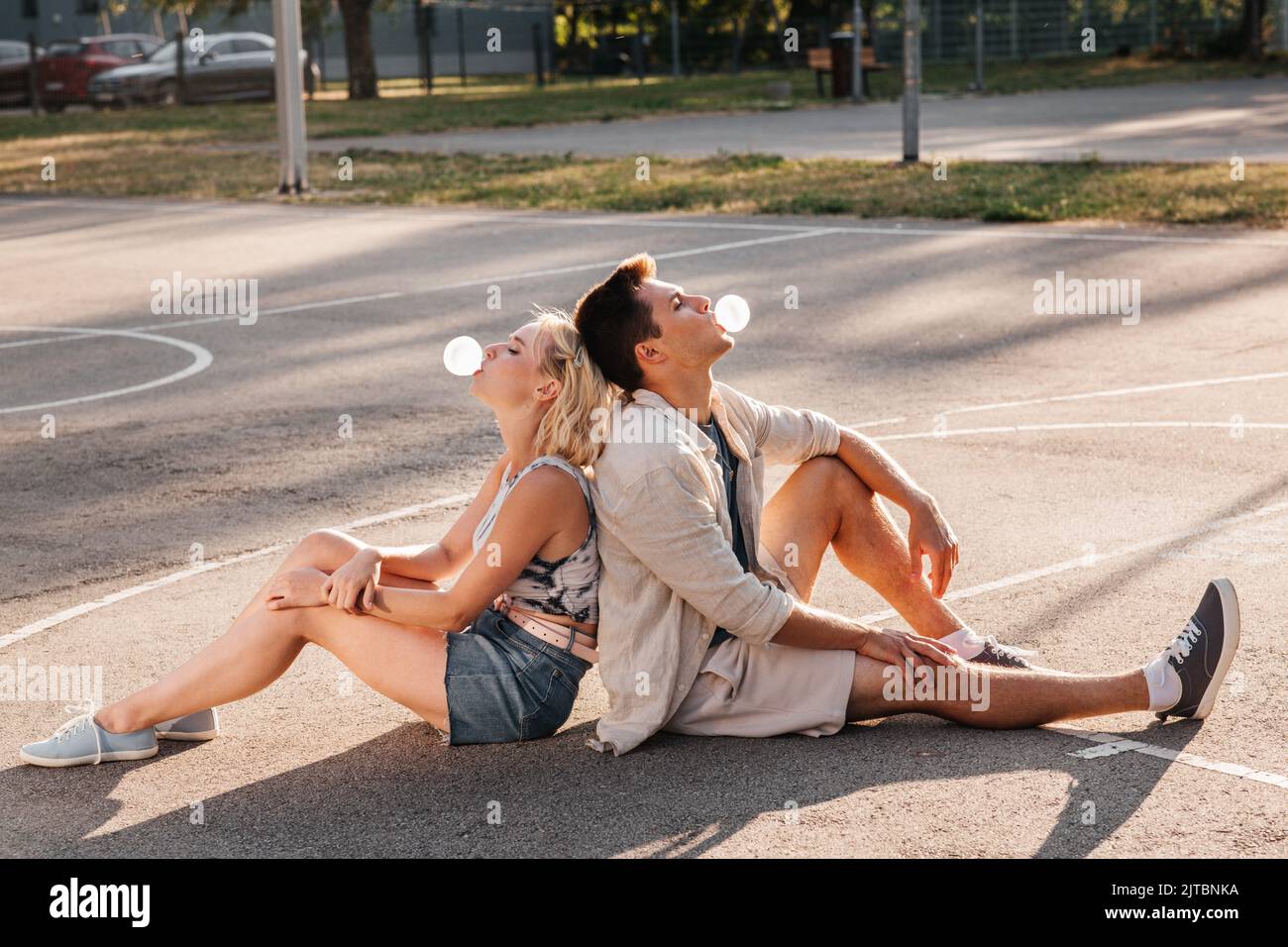 Pärchen sitzt auf dem Boden und bläst Blasengummis Stockfoto