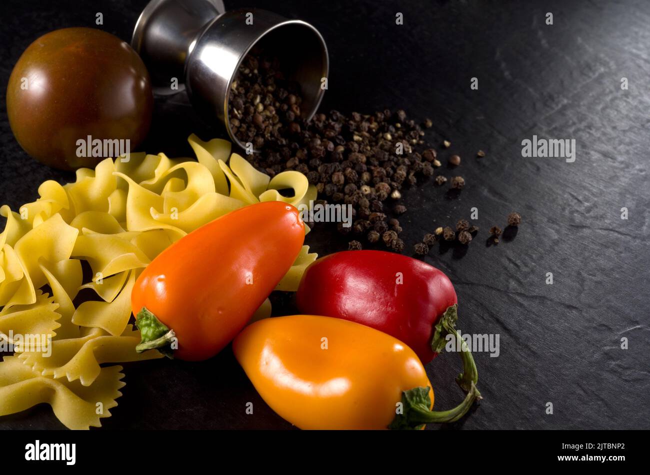 Makrobild von italienischer Pasta, dunkler Tomate, roten und gelben ...