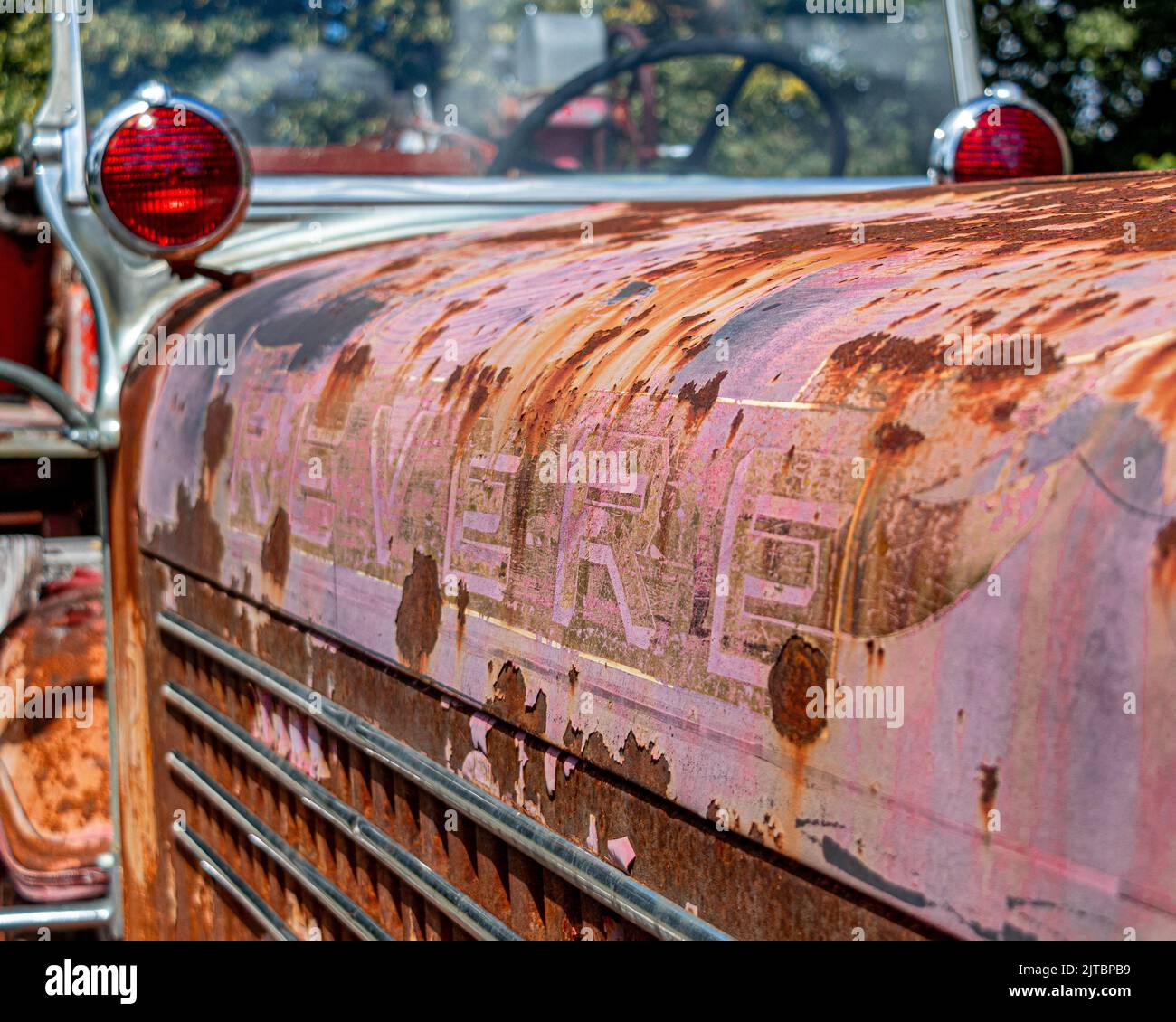 Eine Nahaufnahme eines alten rostigen roten Metalltransportwagens, der unter Sonnenlicht geparkt wurde Stockfoto