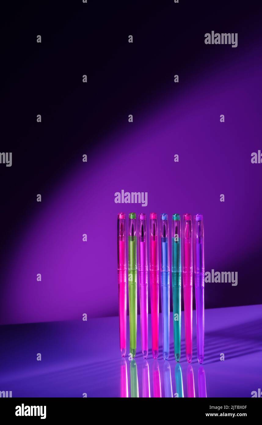 Kreative, minimalistische Komposition, die aus Schulmaterialien in Neonfarben auf einem isolierten schwarzen Hintergrund mit Kopieplatz in der Luft hergestellt wurde. Zurück zur Schule. Minimalistische, konzeptuelle Kunst. Cyberpunk und kosmische Ästhetik. Stockfoto