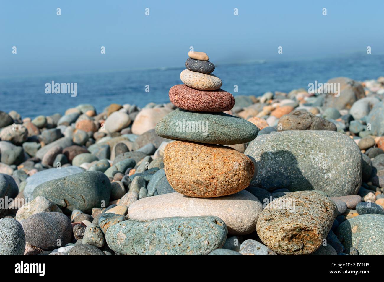 Bunte Steine sind natürlich ausgeglichen auf dem Hintergrund des Meeres. Stockfoto