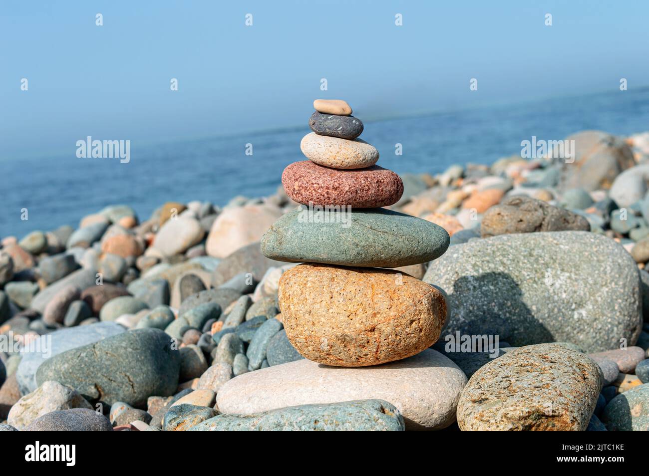 Bunte Steine sind natürlich ausgeglichen auf dem Hintergrund des Meeres. Stockfoto