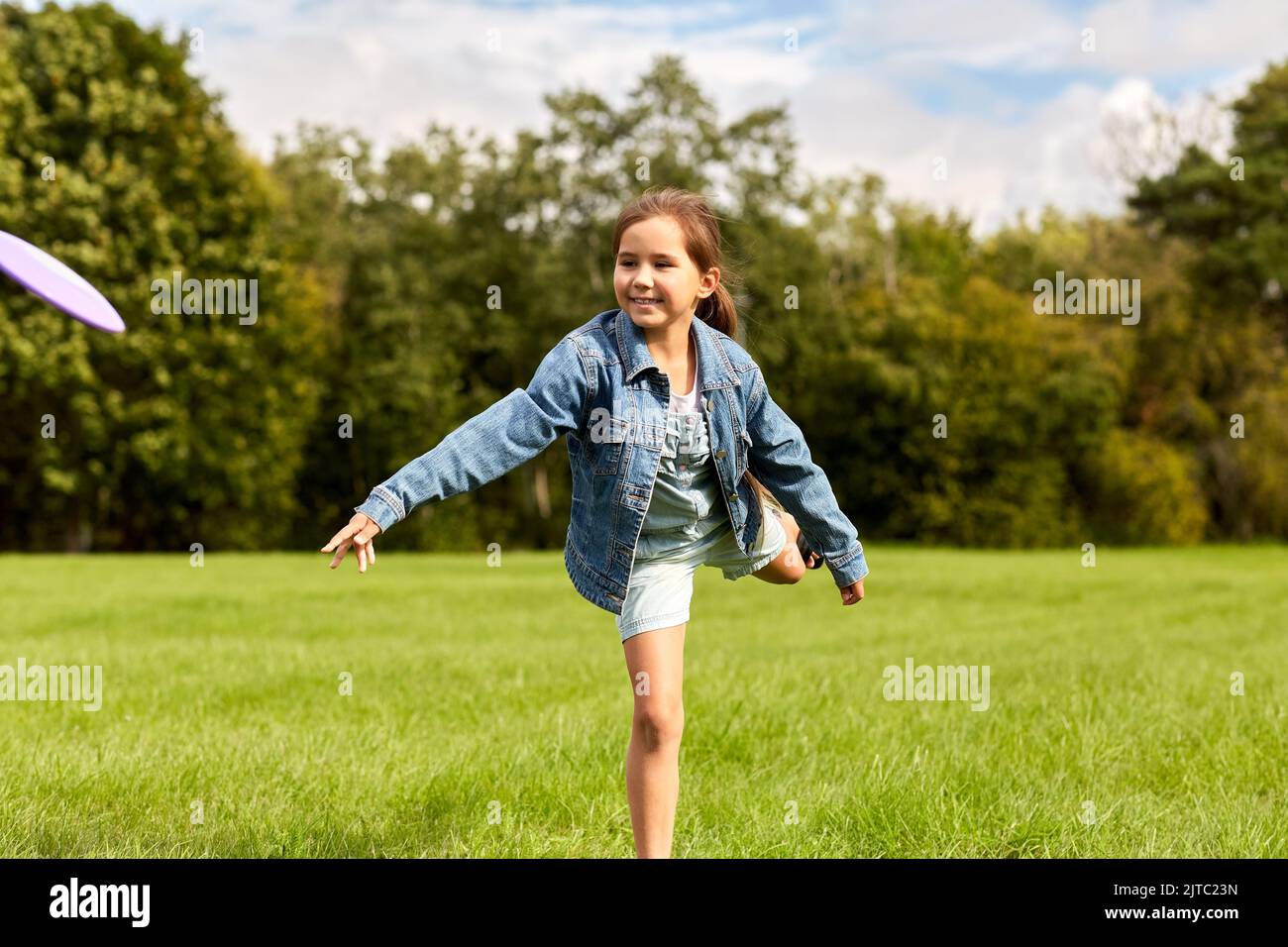 Glückliches Mädchen, das im Park mit fliegender Scheibe spielt Stockfoto