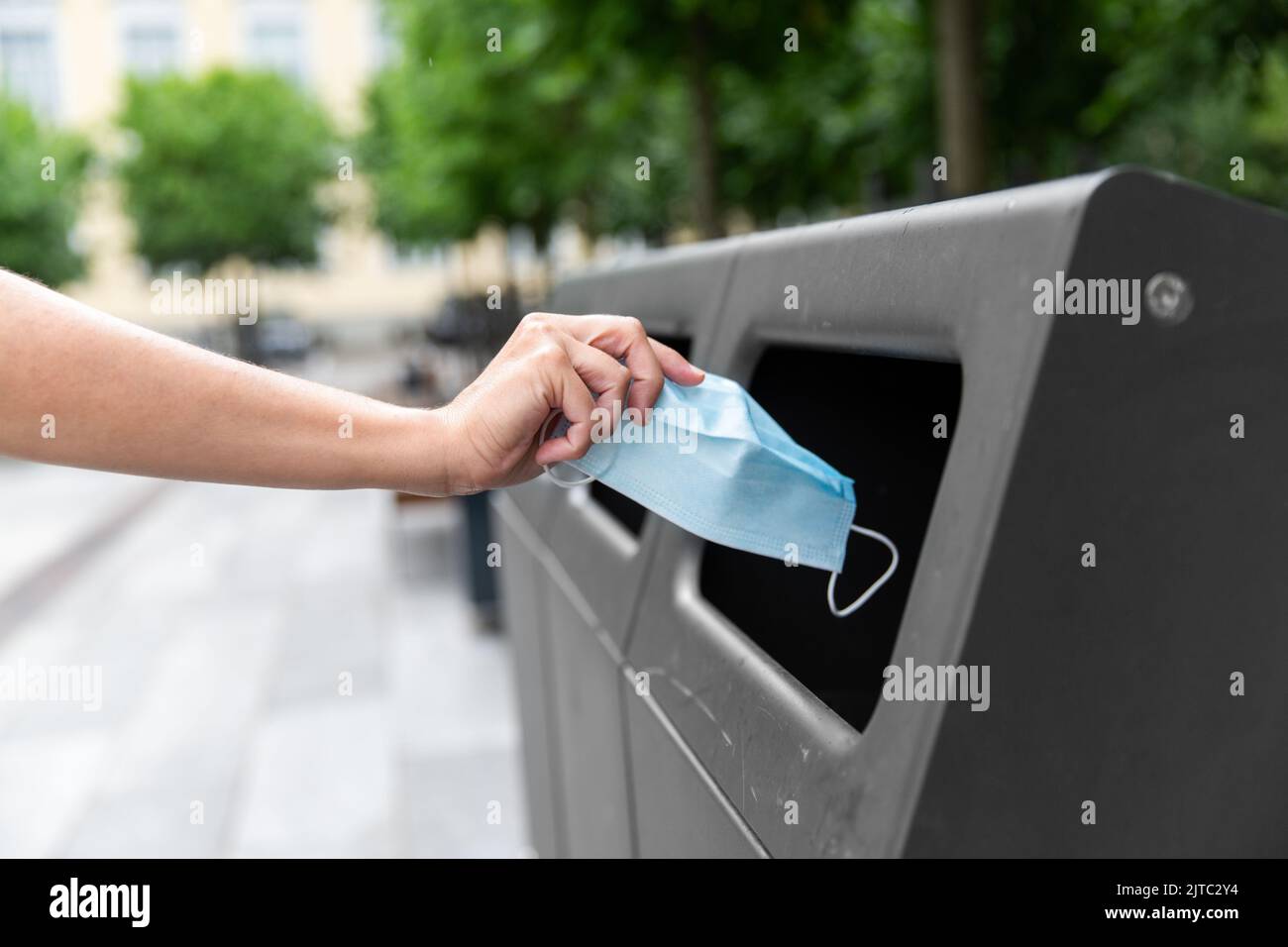 Nahaufnahme der Hand werfen gebrauchte Maske in Müll Stockfoto