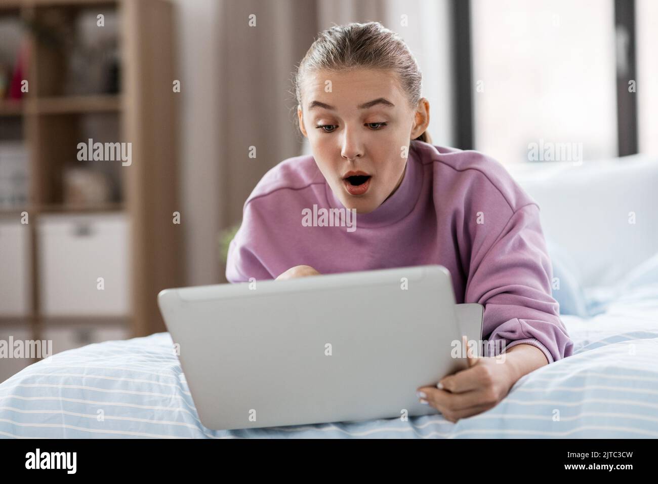 Überrascht Mädchen mit Laptop-Computer zu Hause Stockfoto