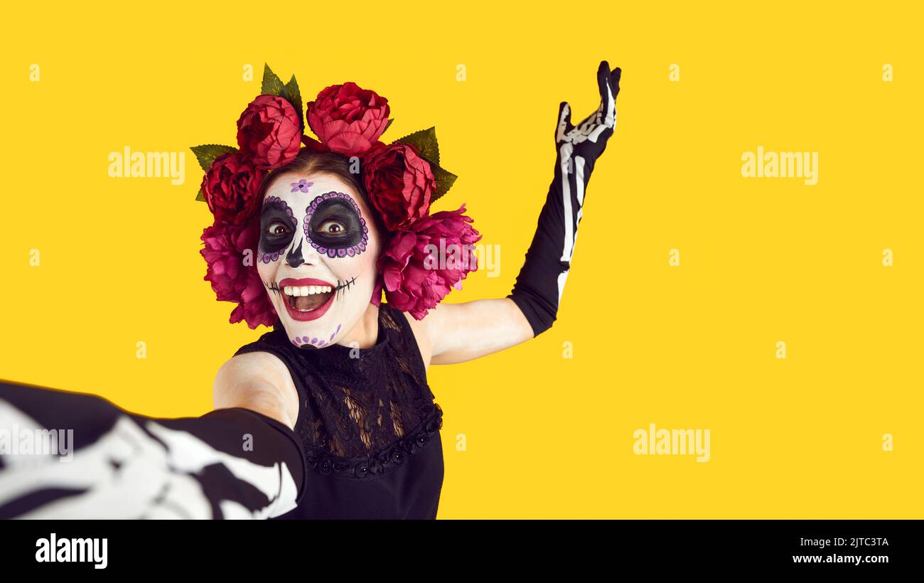 Frau mit gemaltem Schädel auf dem Gesicht nimmt Selfie während der Feier des Tages der Toten oder Halloween. Stockfoto