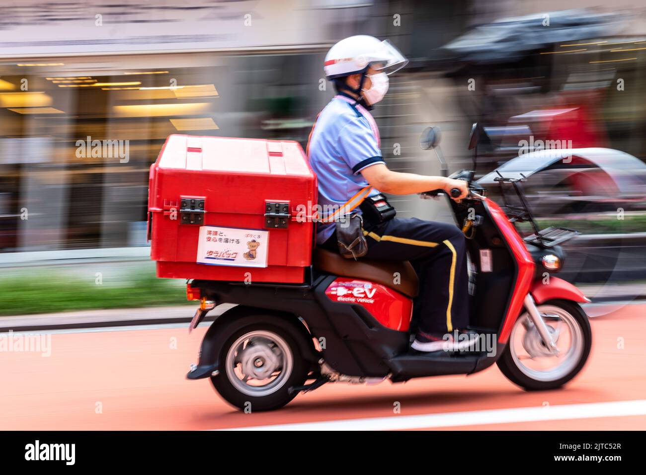 Ein japanischer Postarbeiter liefert die Post mit einem Elektroroller in der Nähe des Sensoji-Tempels in Asakusa, Tokio, Japan. Stockfoto