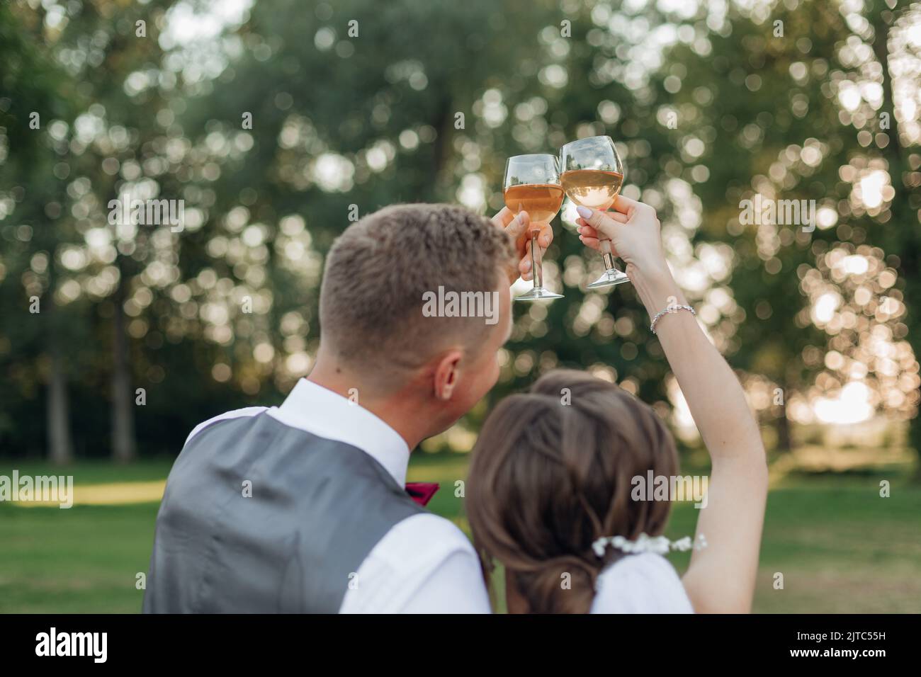 Freuen Sie sich auf ein glückliches verheiratetes Brautpaar im Hochzeitskleid und einen Bräutigam im Anzug, der zusammen Sekt trinkt Stockfoto