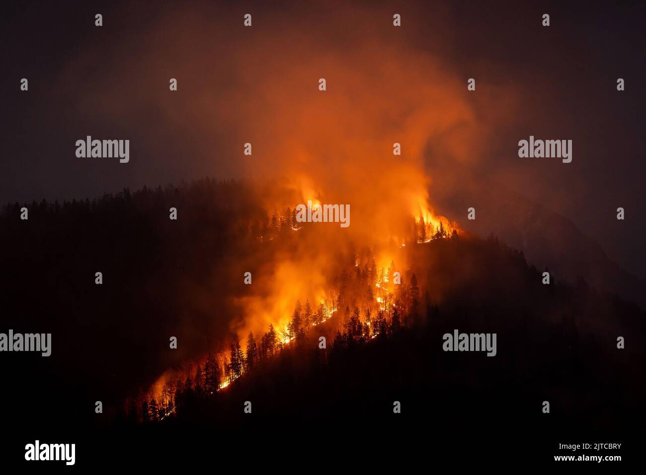 Rauch steigt nach einem Waldbrand über einem Berggebiet, bedroht Gesundheit und Artenvielfalt, Luftaufnahme. Stockfoto