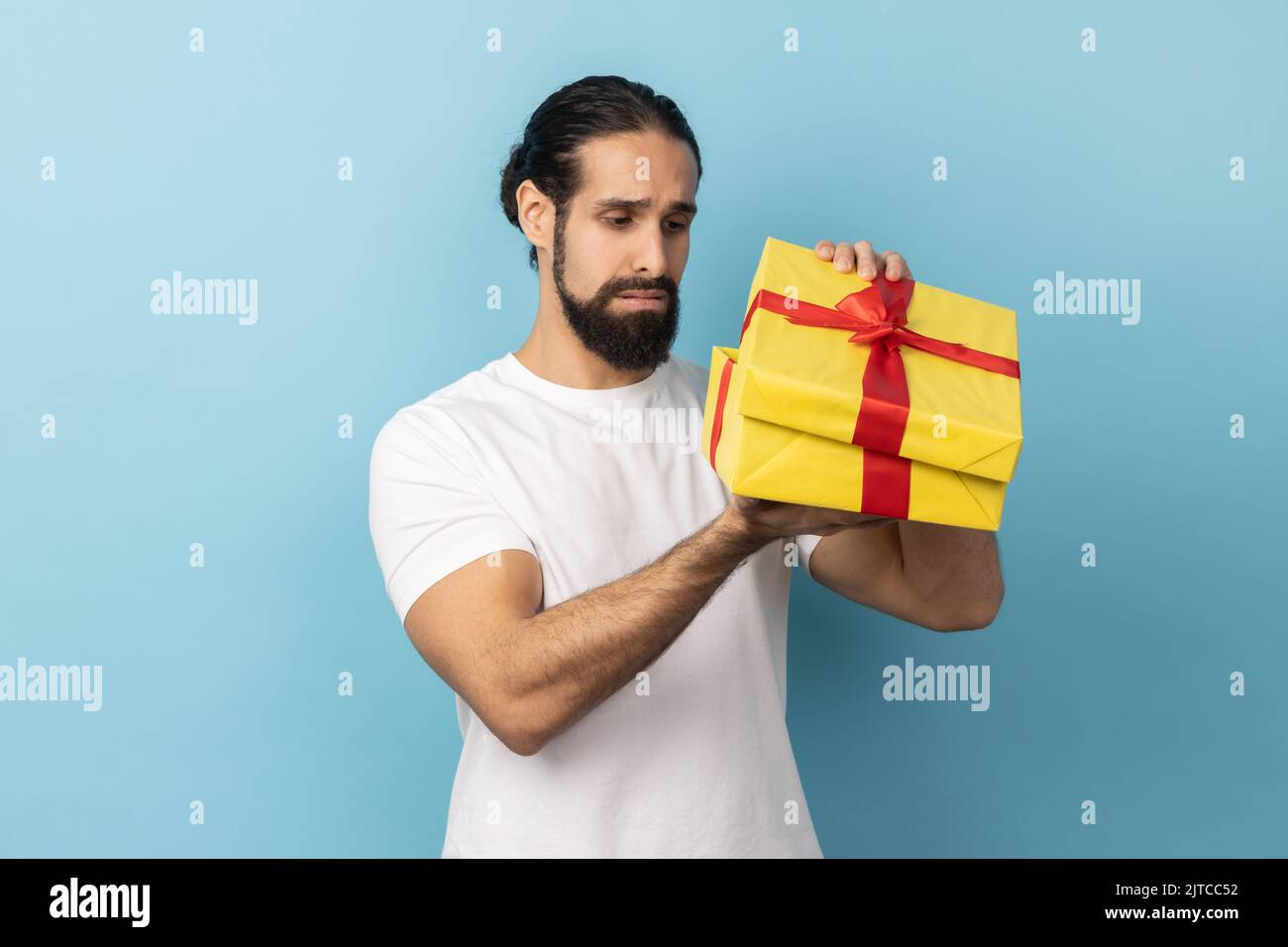 Porträt eines unglücklichen Mannes mit Bart trägt weißes T-Shirt Blick in Geschenk-Box und zum Ausdruck bringen Traurigkeit, hoffte, ein weiteres Geschenk zu bekommen. Innenaufnahme des Studios isoliert auf blauem Hintergrund. Stockfoto Porträt eines unglücklichen Mannes mit Bart trägt weißes T-Shirt Blick in Geschenk-Box und zum Ausdruck bringen Traurigkeit, hoffte, ein weiteres Geschenk zu bekommen. Innenaufnahme des Studios isoliert auf blauem Hintergrund. Stockfoto