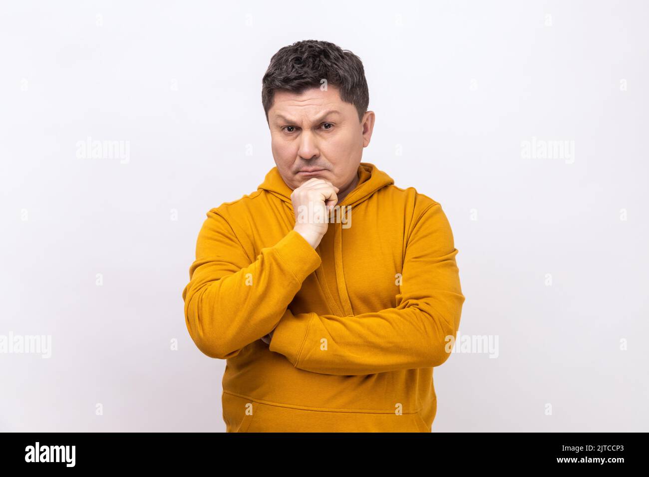 Hmm, ich muss nachdenken. Porträt eines Mannes mittleren Alters, der nach oben schaut, Kinn hält und gutet, die Kamera anschaut und einen Hoodie im urbanen Stil trägt. Innenaufnahme des Studios isoliert auf weißem Hintergrund. Stockfoto