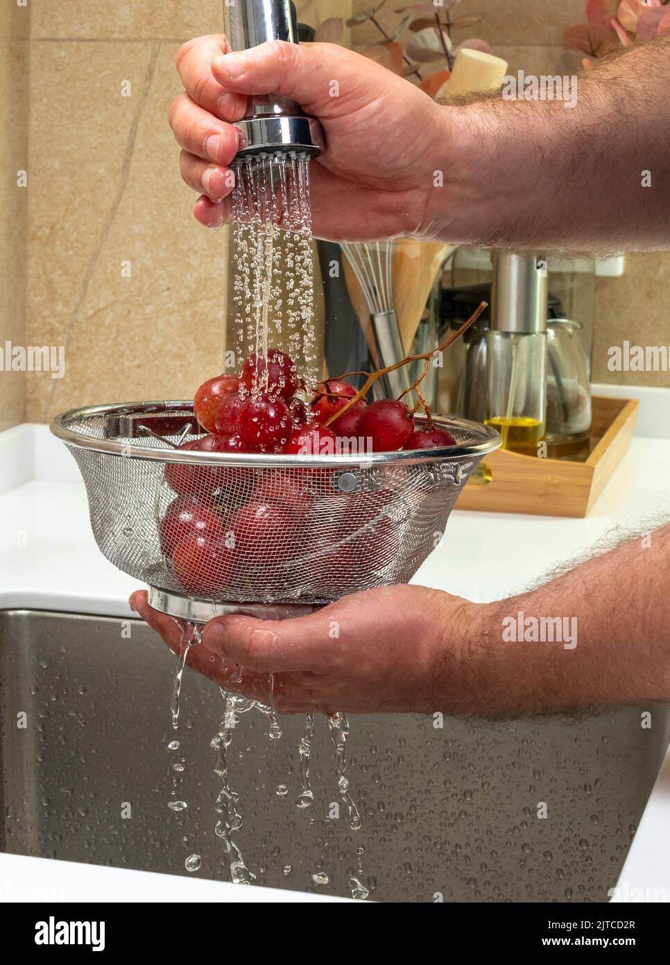 Rote Trauben unter einem starken Wasserstrahl mit Spritzern Stockfoto