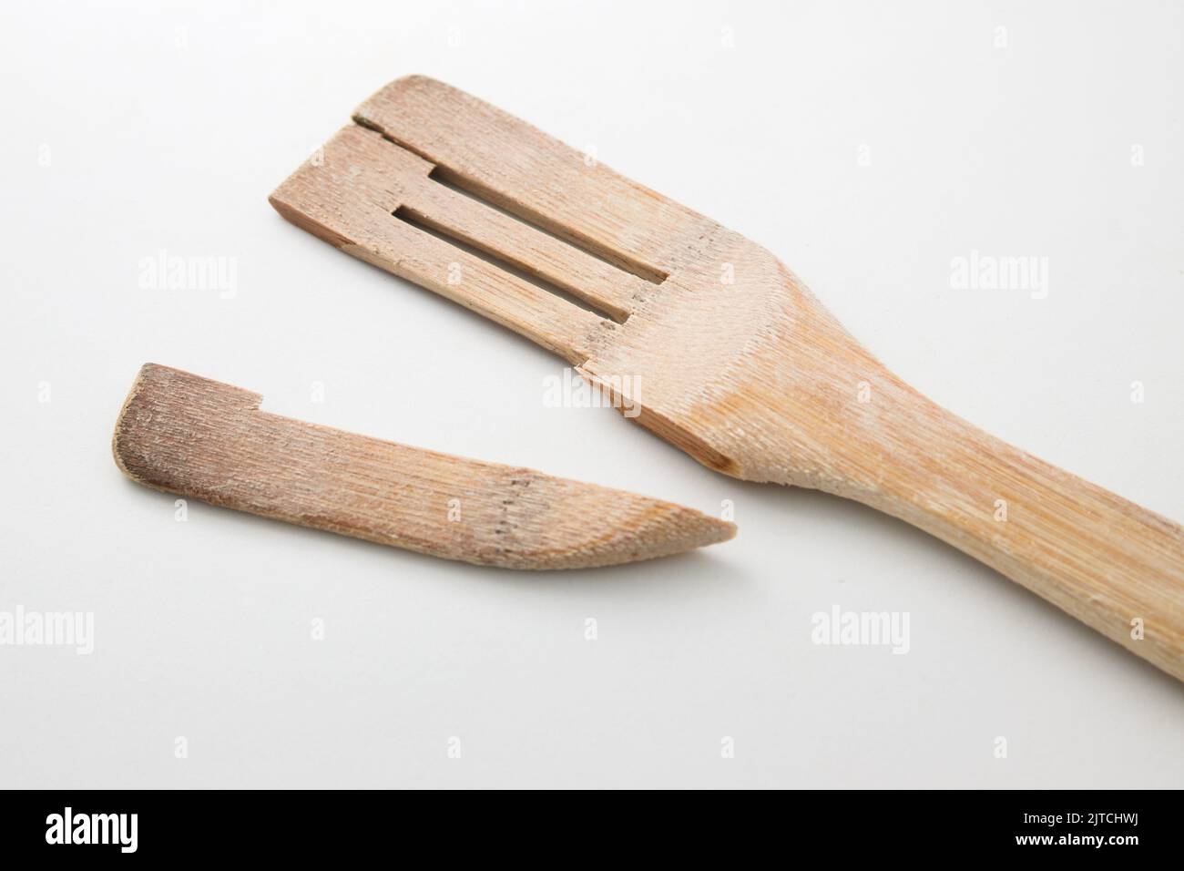 Eine Nahaufnahme eines gebrauchten Holzspatels, der auf einem neutralweißen Hintergrund an seinem schwächsten Teil eingerastet ist Stockfoto