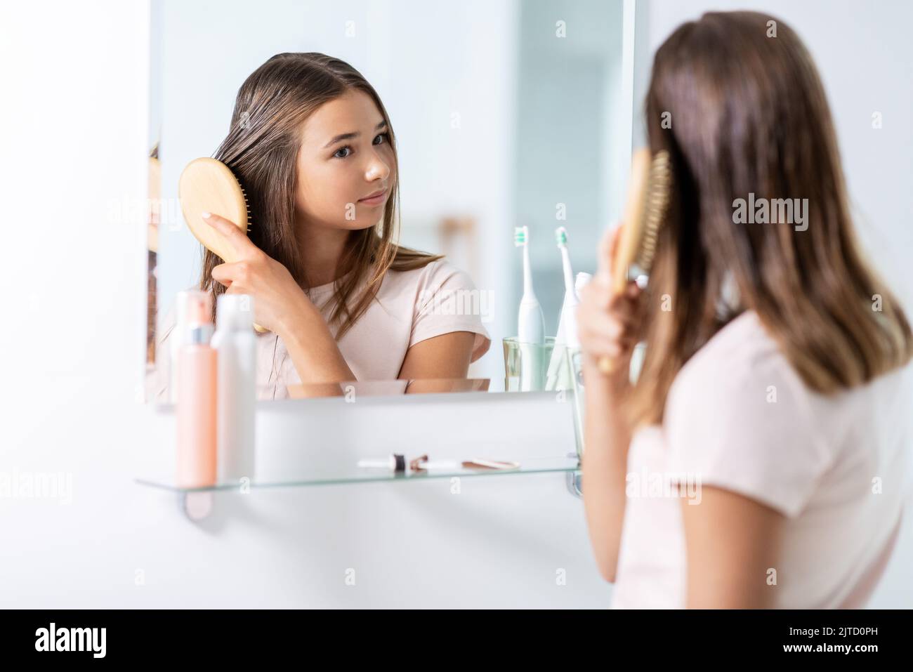 Teenager-Mädchen putzt Haare mit Kamm im Badezimmer Stockfoto