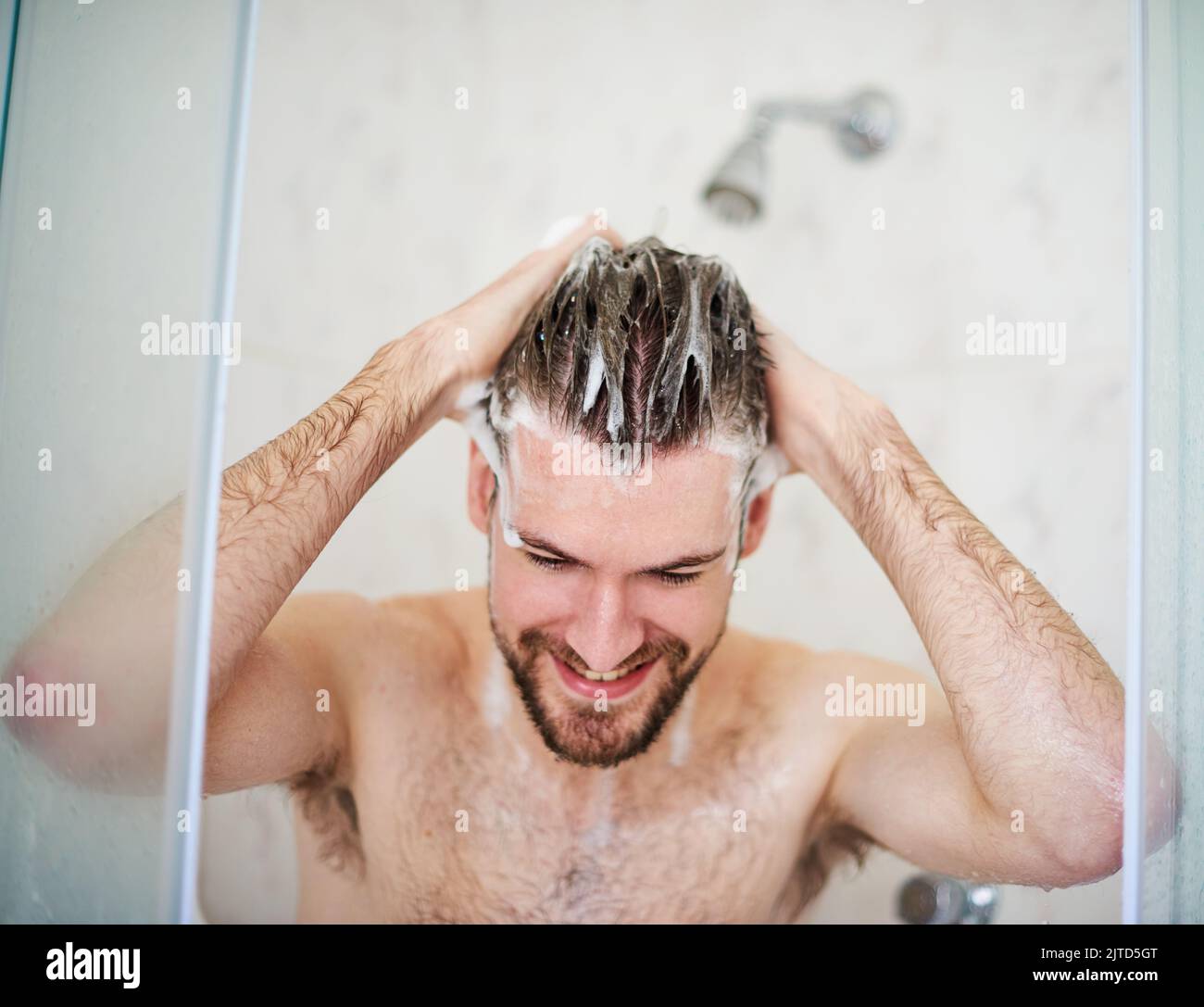 Shampoo und Zustand für eine saubere Kopfhaut. Ein hübscher junger Mann, der zu Hause duschen kann. Stockfoto