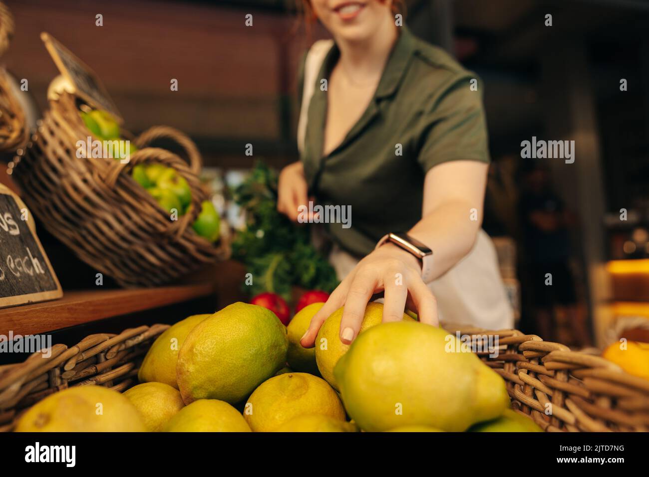 Ein zufriedener Kunde pflückt im Frischebereich eines Lebensmittelladens ein paar Bio-Früchte. Nicht erkennbare Frau Lebensmitteleinkäufe in einem trendigen Supermar Stockfoto