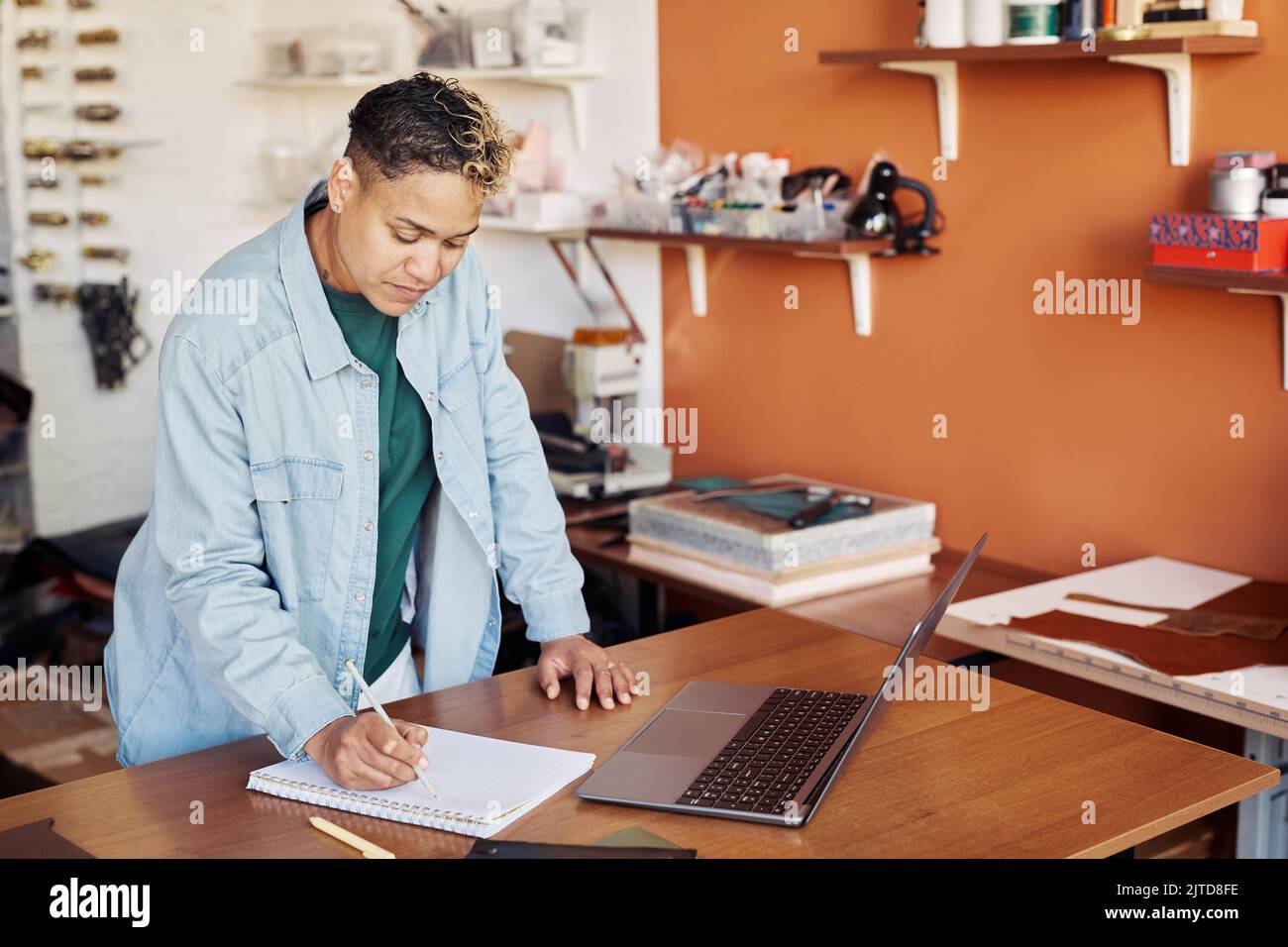 Porträt einer schwarzen Frau, die in einem Planer schreibt, während sie die Manufaktur für kleine Unternehmen verwaltet, Kopierfläche Stockfoto