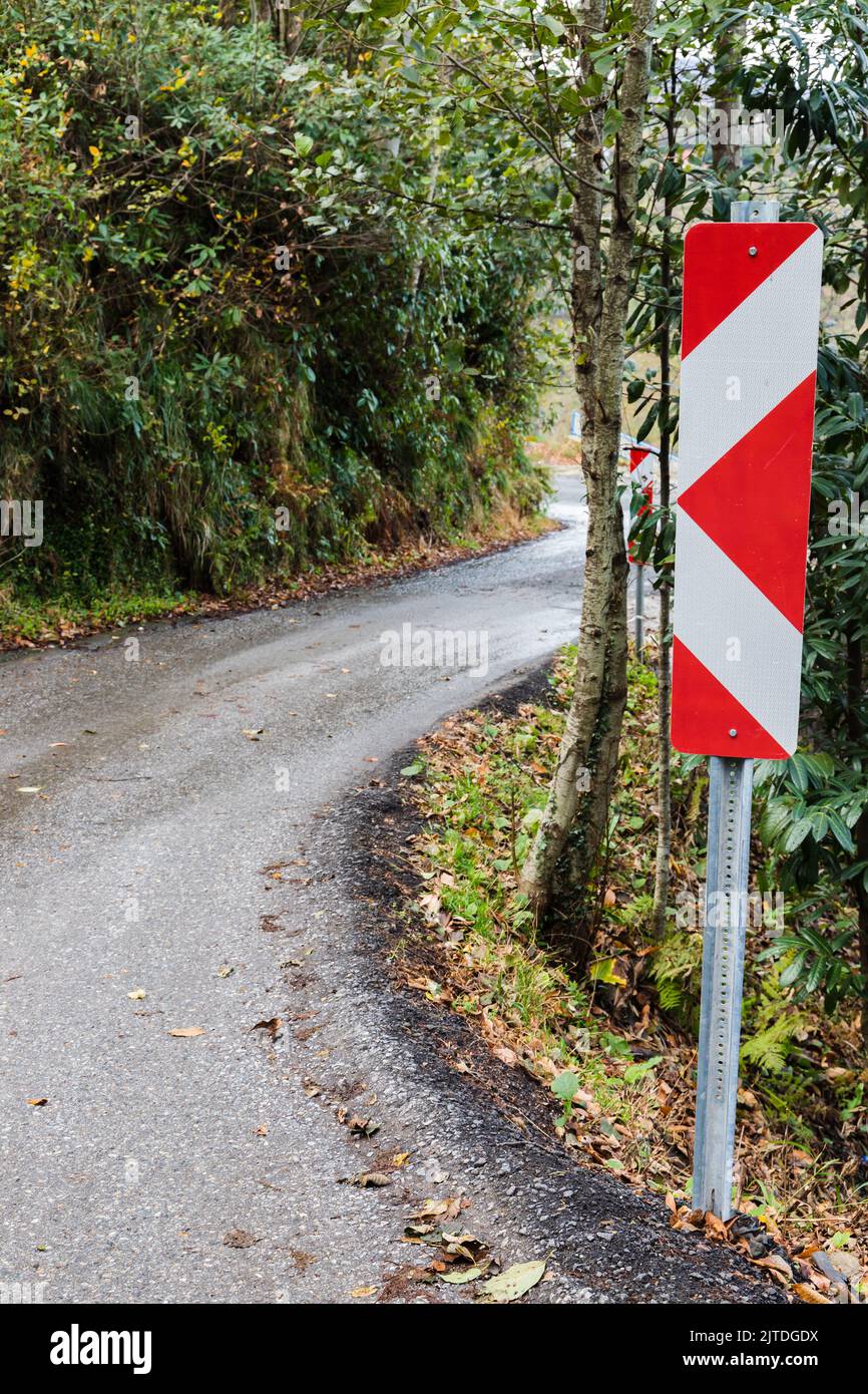Abbiegehichtung, Schutzschild auf einer Straße an einer abbiegenden Bergstraße montiert, vertikales Foto Stockfoto