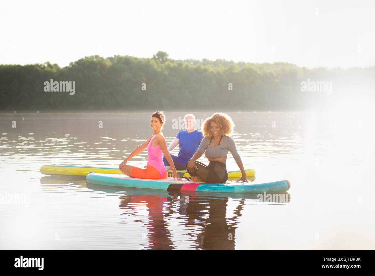 Gruppe von Menschen, die sich um ihre psychische Gesundheit kümmern, indem sie sich auf SUP-Boards entspannen Stockfoto