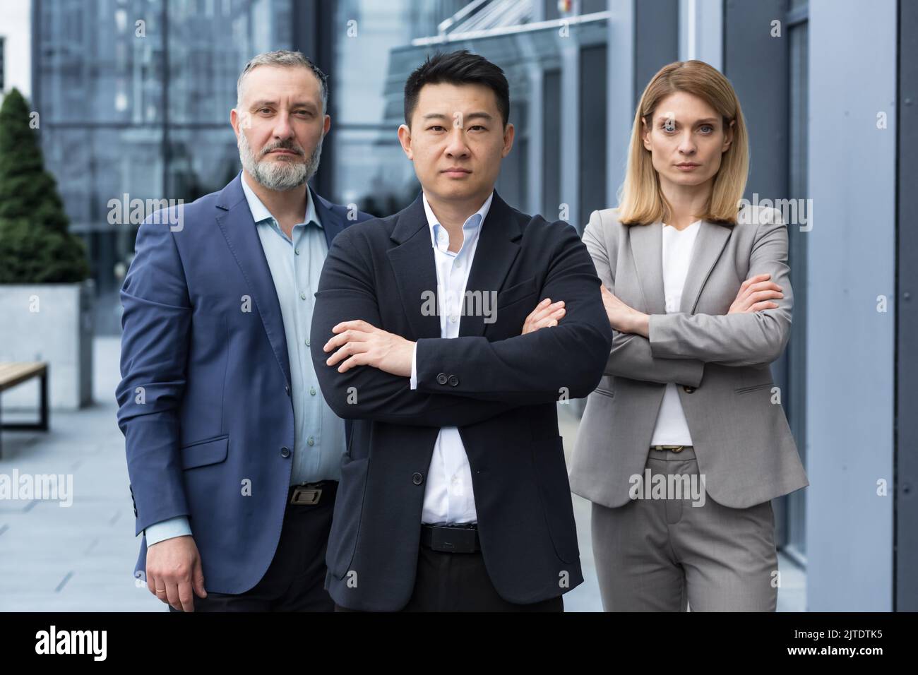 Ein erfolgreiches und seriöses Team aus drei Geschäftsleuten, Männer und Frauen, die sich mit gekreuzten Armen auf die Kamera konzentrierten, ein Porträt von Mitarbeitern außerhalb des Bürogebäudes Stockfoto