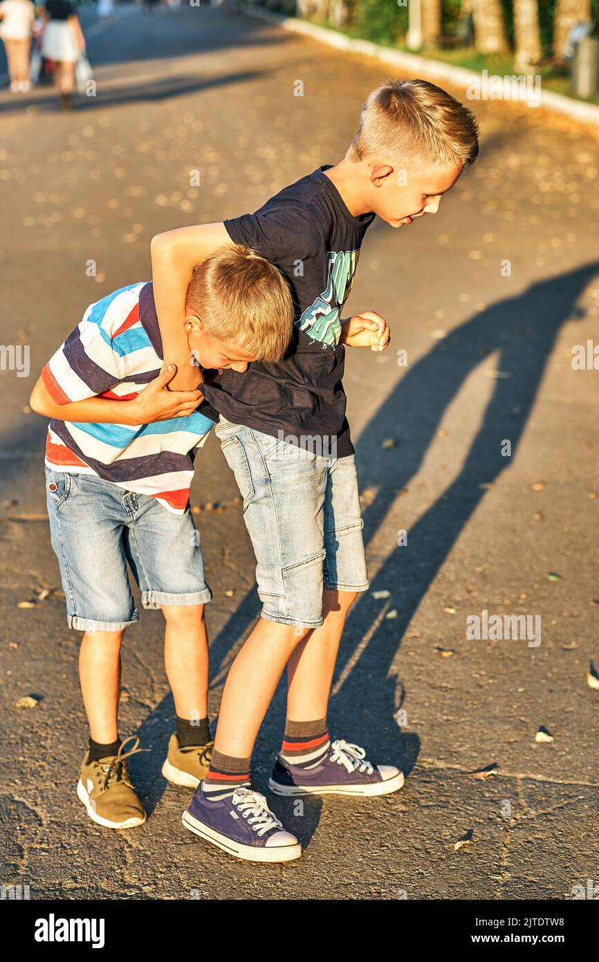 Brüder ringen auf dem Bürgersteig im öffentlichen Park. Fröhliche Schüler haben Spaß im öffentlichen Park am Sommerabend Stockfoto