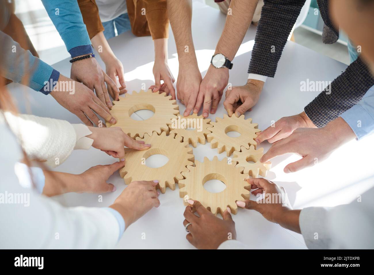 Nahaufnahme von hölzernen Zahnrädern, die Geschäftsleute während der Teambuilding-Sitzung miteinander verbinden. Stockfoto