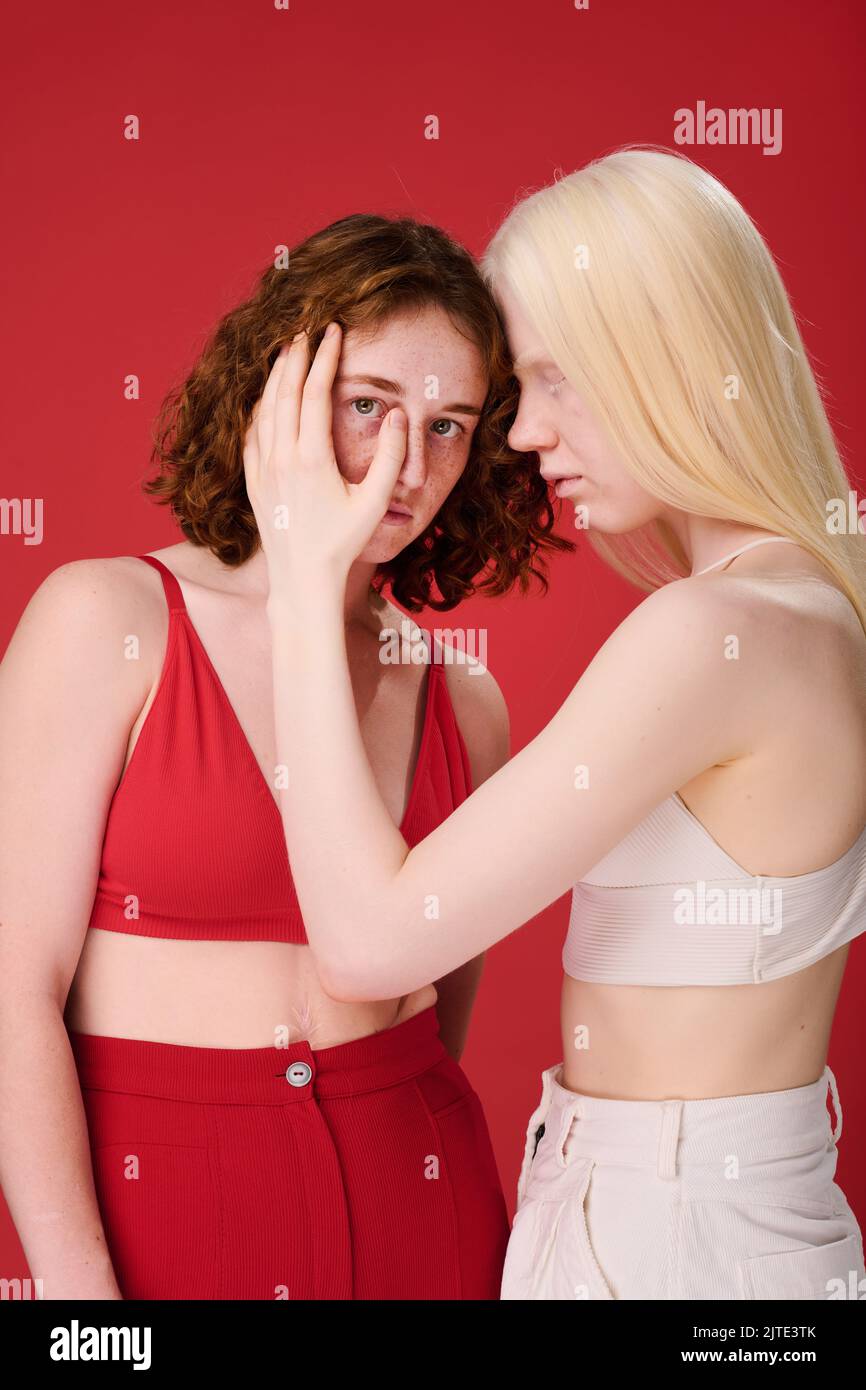 Portrait von zwei Mädchen mit natürlicher Schönheit und ungewöhnlichen Auftritten vor rotem Hintergrund Stockfoto