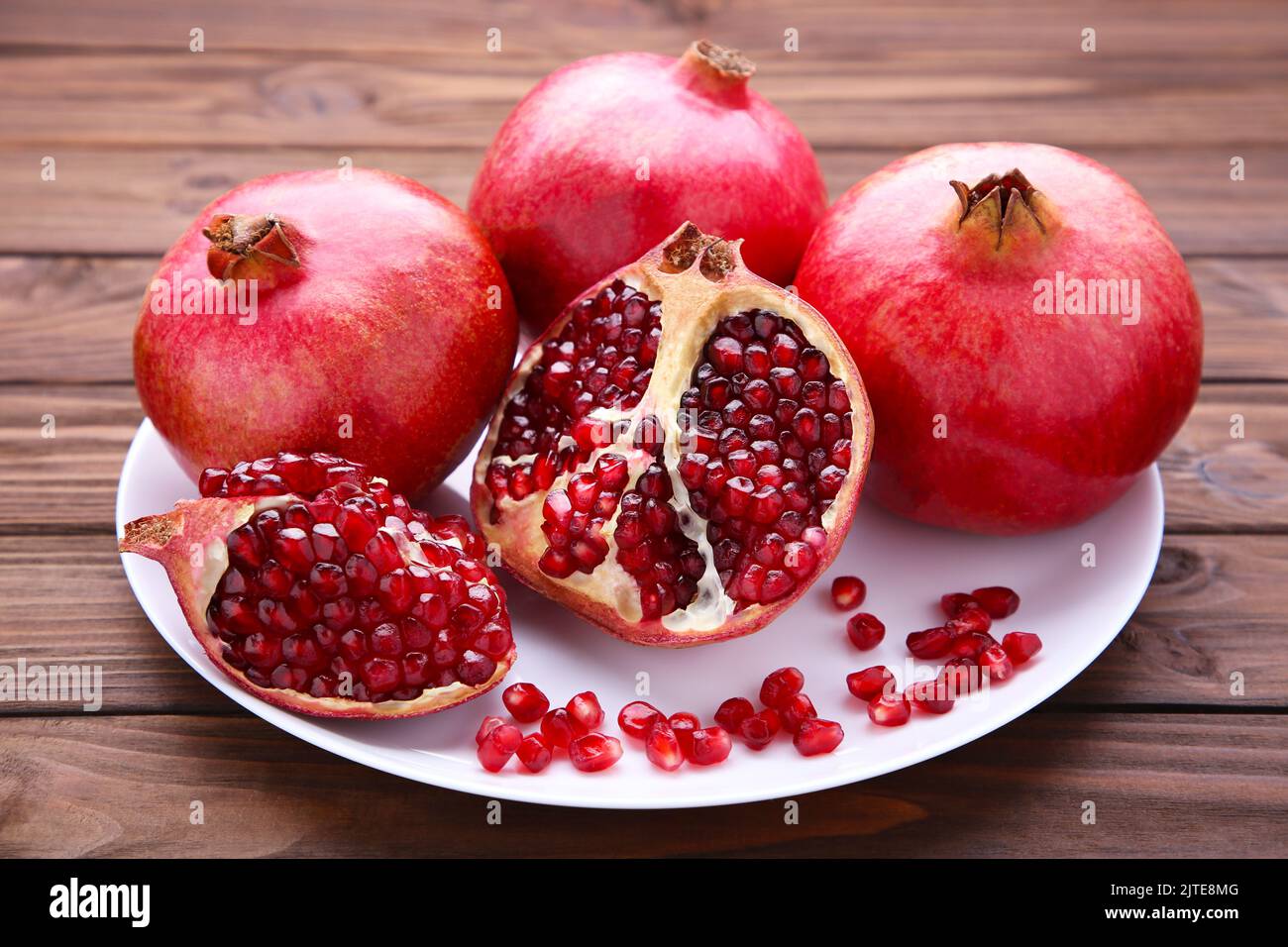 Granatäpfel auf Teller auf braunem Hintergrund Stockfoto