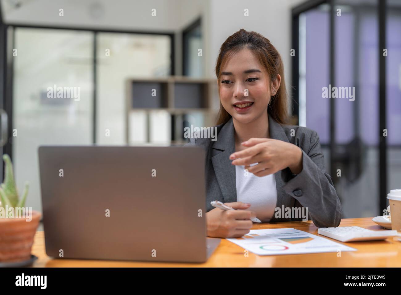 Porträt einer lächelnden asiatischen selbstständigen Freiberuflerin bei der Arbeit mit Laptop-Forschungsprojekt. Positive motivierte junge schwarze Dame entfernt Student Stockfoto