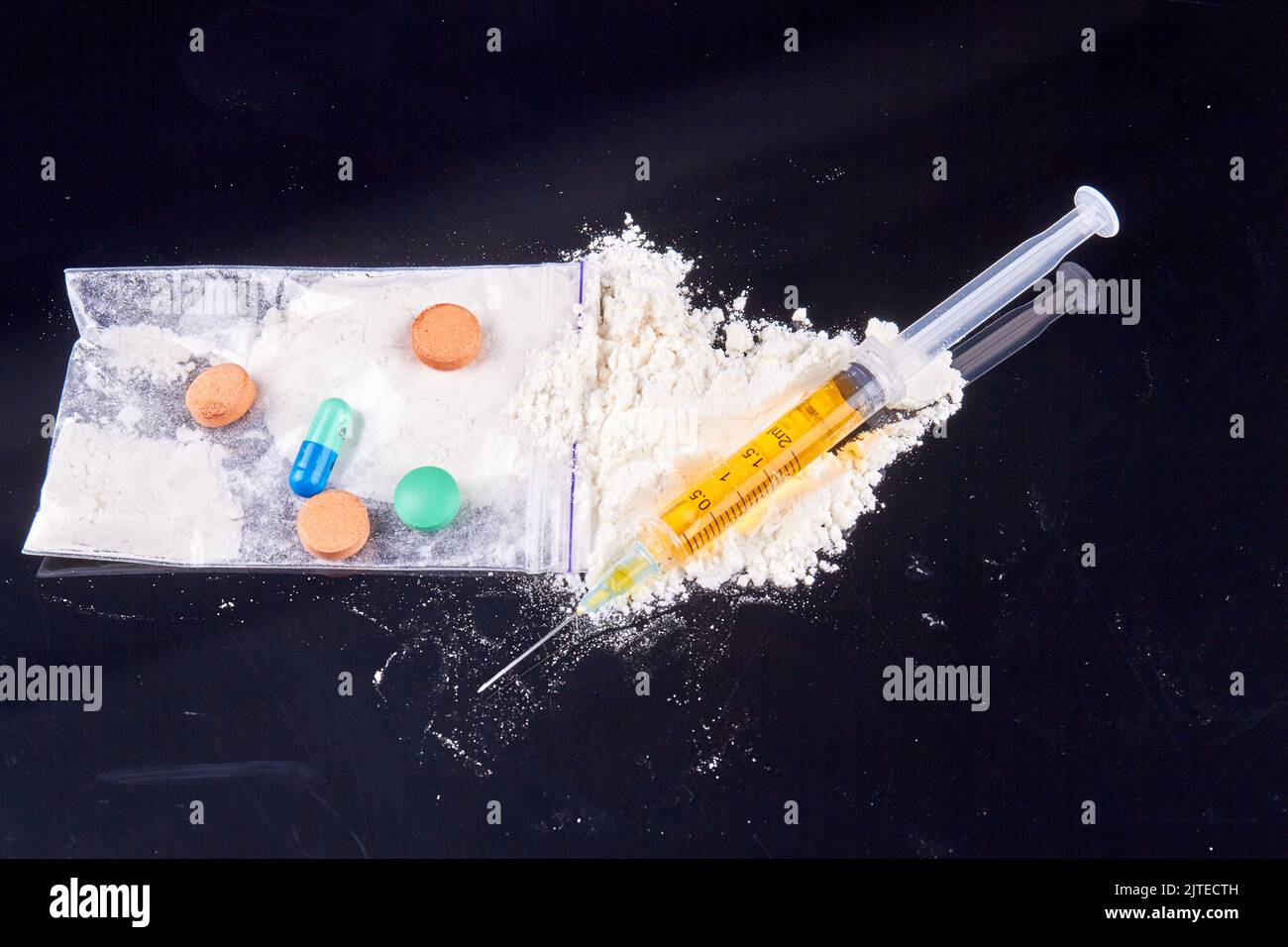Nahaufnahme Stapel von verschiedenen Medikamenten und Spritze auf schwarzem Hintergrund. Drogenkonsum und Suchtkonzept. Stockfoto
