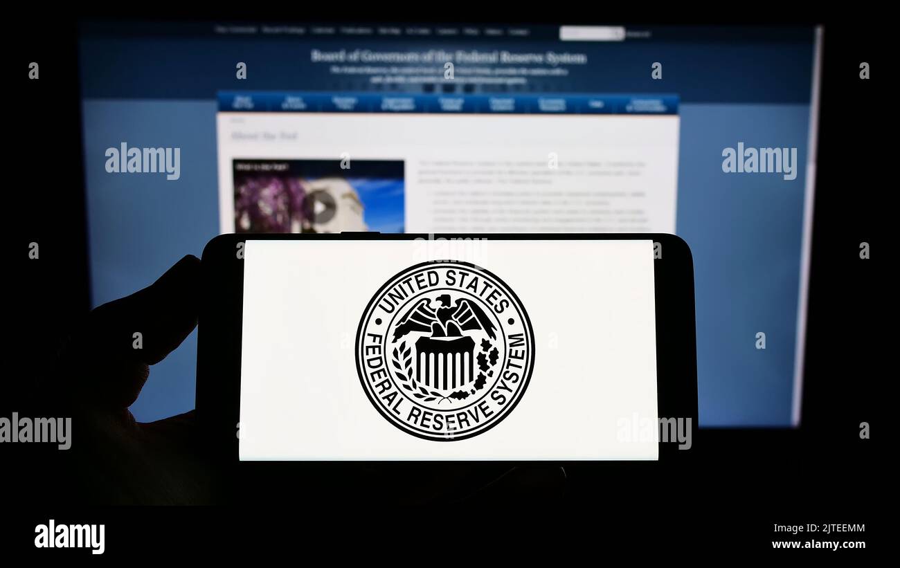 Person, die das Smartphone mit dem Siegel des US-amerikanischen Federal Reserve System (Fed) auf dem Bildschirm vor der Website hält. Konzentrieren Sie sich auf die Telefonanzeige. Stockfoto
