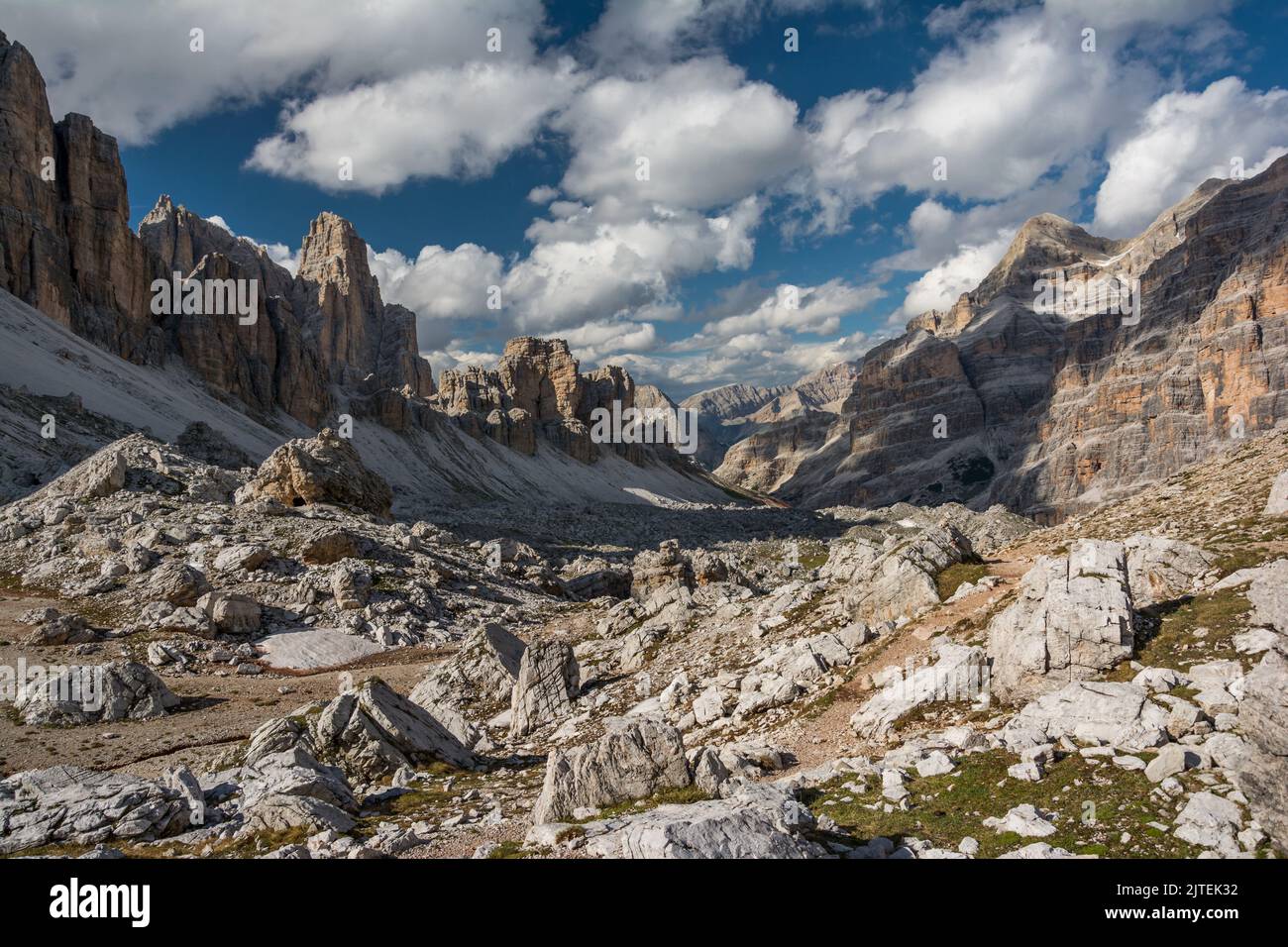 Langes Tal mit vielen weißen Steinen, weiße Wolken am Himmel über hohen Dolomiten-Bergen Stockfoto