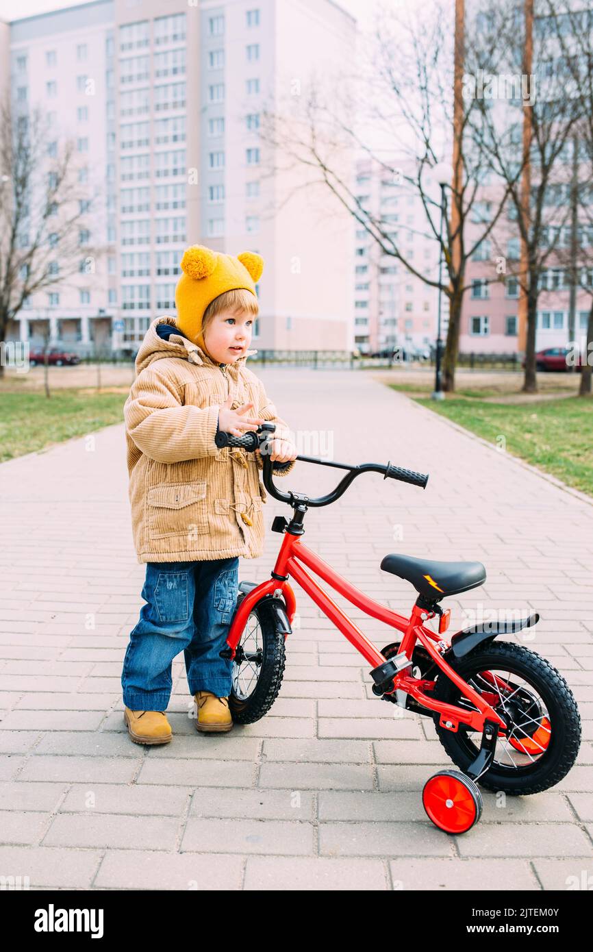 Ein kleines Kind lernt im Frühjahr zum ersten Mal in der Stadt Fahrrad zu fahren Stockfoto