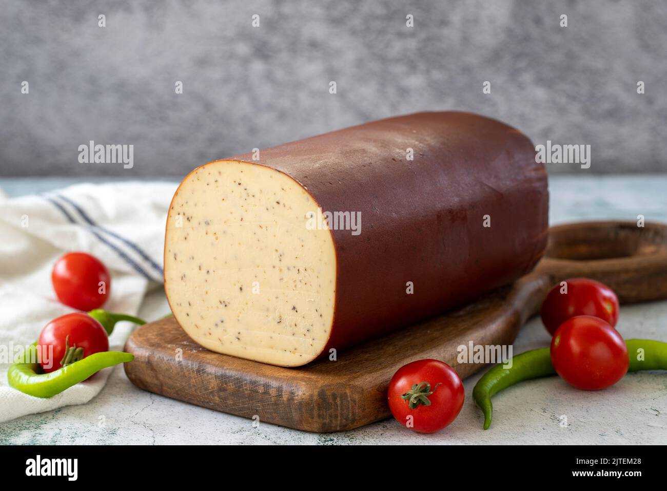 Schwarzer Pfeffer Geräucherter Käse. Holländischer geräucherter Käse auf Steinhintergrund. Nahaufnahme Stockfoto