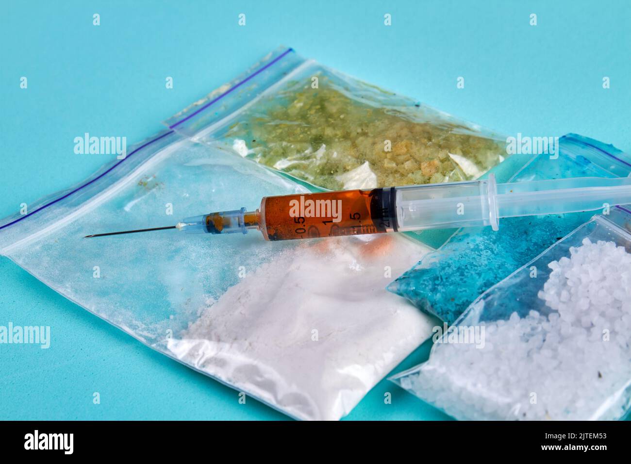 Spritze und Pakete mit verschiedenen Medikamenten isoliert auf blauem Hintergrund. Viele verschiedene Betäubungsmittel. Stockfoto